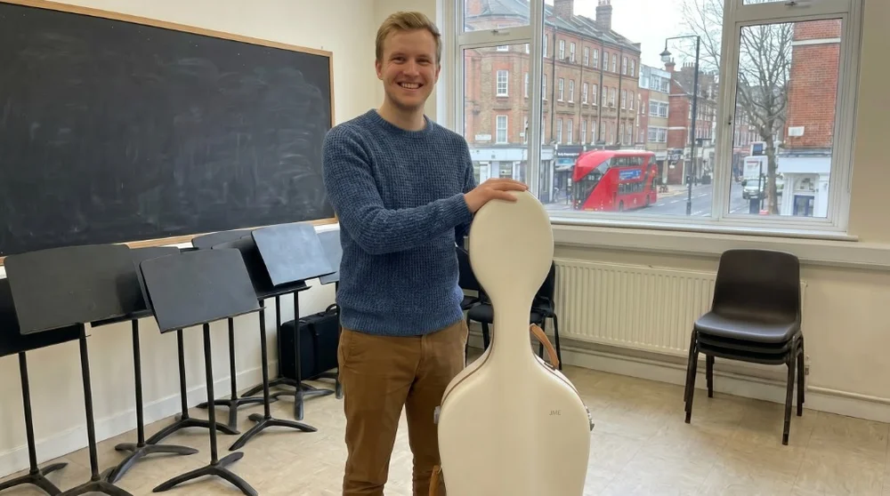 Musician with JML white cello case in London classroom